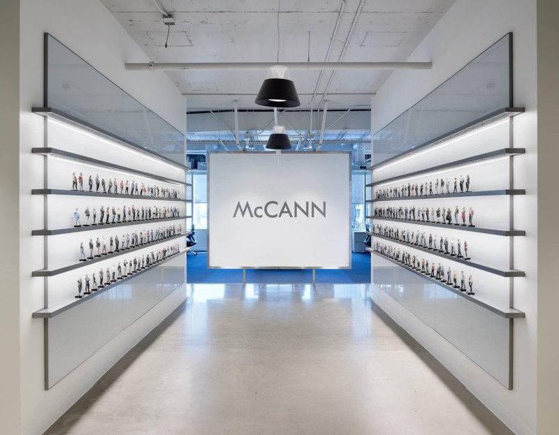 McCann advertising agency figurine wall installation showing rows of 3D scanned employee figurines in a modern office corridor